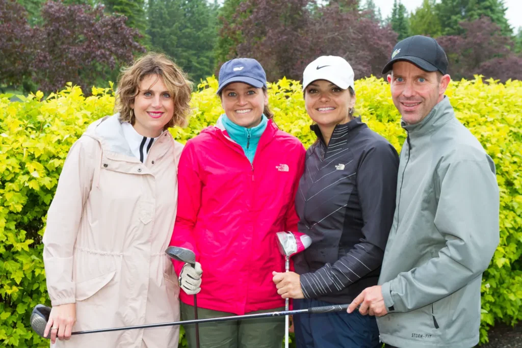 Quatre golfeurs posant avec clubs en extérieur