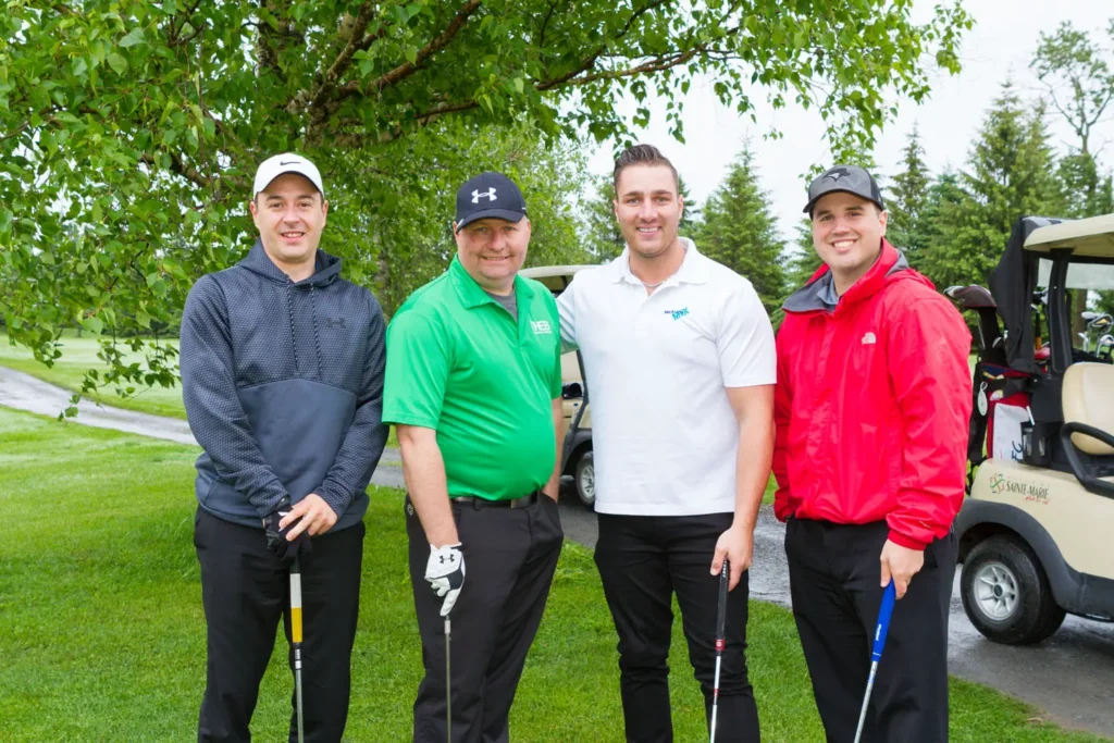 Quatre hommes posant sur un parcours de golf