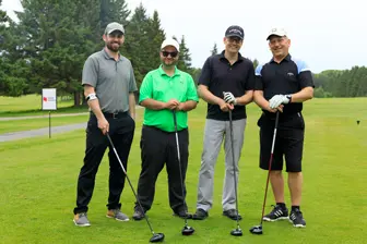 Quatre hommes avec clubs sur un parcours de golf