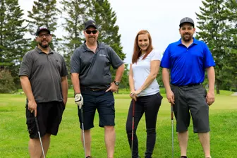 Quatre golfeurs posant sur un parcours verdoyant