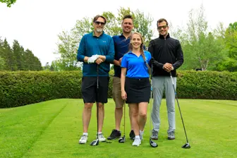 Quatre golfeurs posant sur un parcours verdoyant