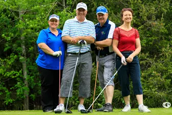 Quatre golfeurs souriants sur un parcours verdoyant
