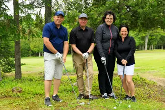 Quatre golfeurs posant sur un parcours verdoyant