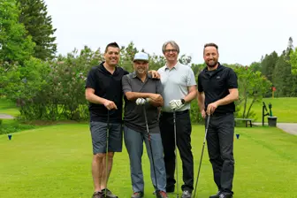 Quatre hommes posent sur un terrain de golf