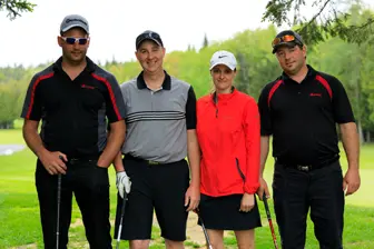 Quatre golfeurs posant sur un parcours verdoyant