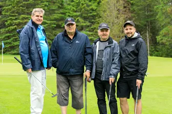 Quatre hommes avec clubs sur un golf