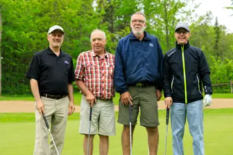Quatre hommes avec clubs sur un parcours de golf