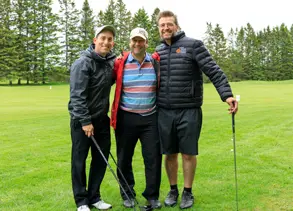 Trois hommes posant sur un terrain de golf