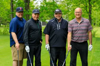 Quatre hommes posent sur un parcours de golf