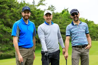 Trois hommes souriants sur un parcours de golf