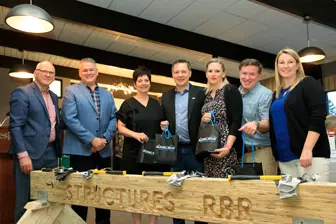 Groupe posant derrière poutre en bois gravée