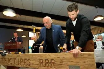 Deux hommes travaillent sur une poutre en bois