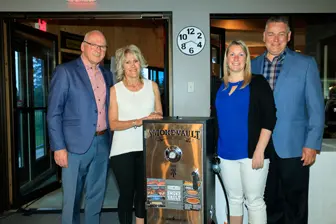 Quatre adultes posent près d'une plaque commémorative