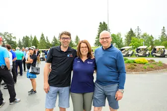 Trois personnes posent lors d’un événement en plein air