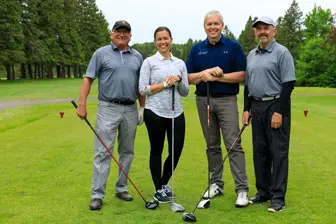 Quatre golfeurs souriants sur un parcours verdoyant