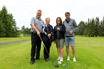 Quatre adultes souriants sur un parcours de golf