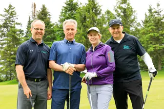 Quatre golfeurs posant sur un parcours verdoyant