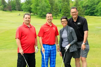 Quatre golfeurs souriants sur un parcours verdoyant