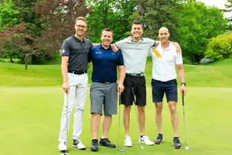 Quatre hommes posant sur un parcours de golf