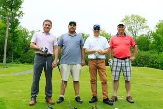Quatre hommes avec clubs sur un golf