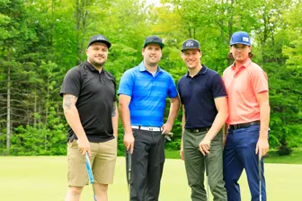 Quatre hommes posant sur un parcours de golf
