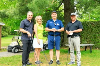 Quatre golfeurs posant sur un parcours verdoyant