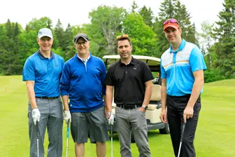 Quatre golfeurs posent sur un parcours verdoyant