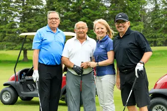 Quatre golfeurs posant sur un parcours verdoyant