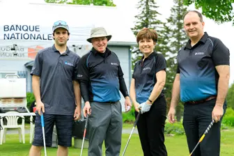 Quatre golfeurs posant sur un parcours