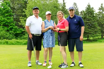 Quatre adultes posant sur un parcours de golf