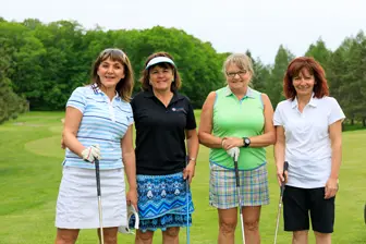 Quatre femmes souriantes sur un parcours de golf