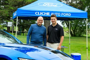 Deux hommes devant stand Ford et voiture bleue