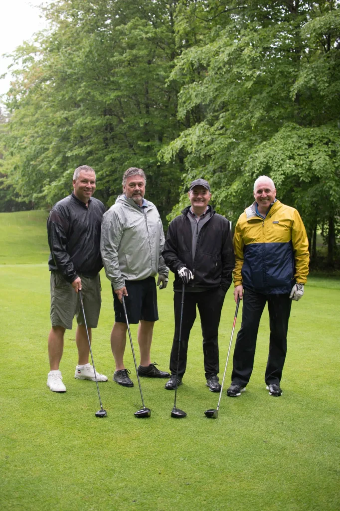 Quatre hommes sur un parcours de golf pluvieux