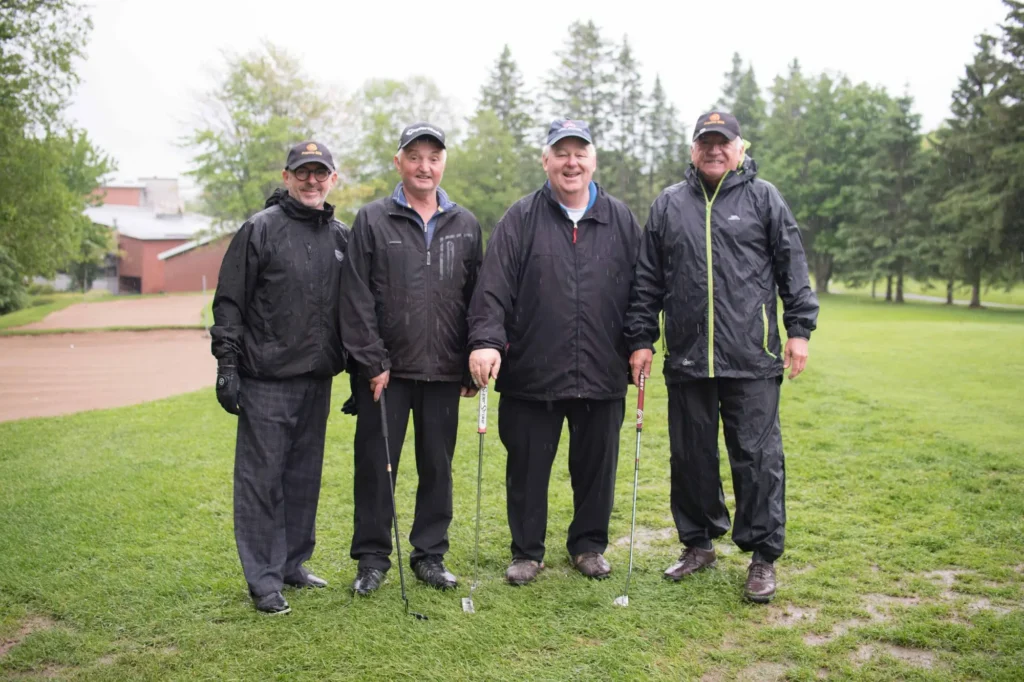 Quatre hommes jouant au golf sous la pluie