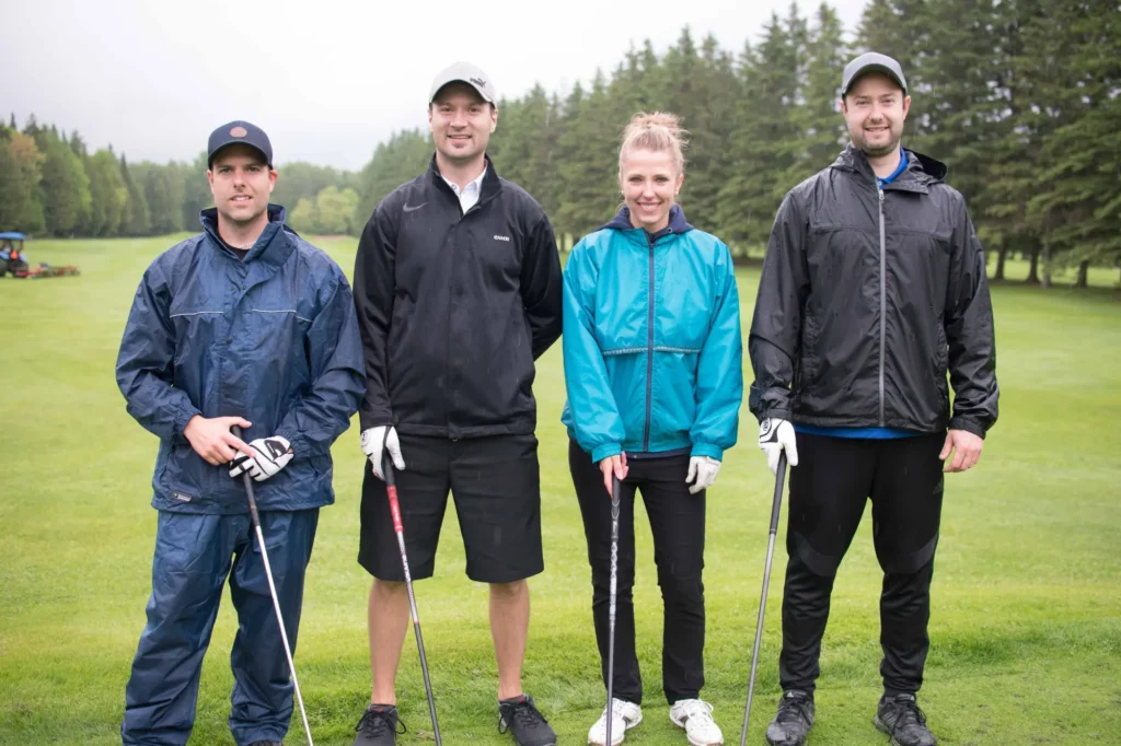 Quatre golfeurs posant sur un parcours verdoyant