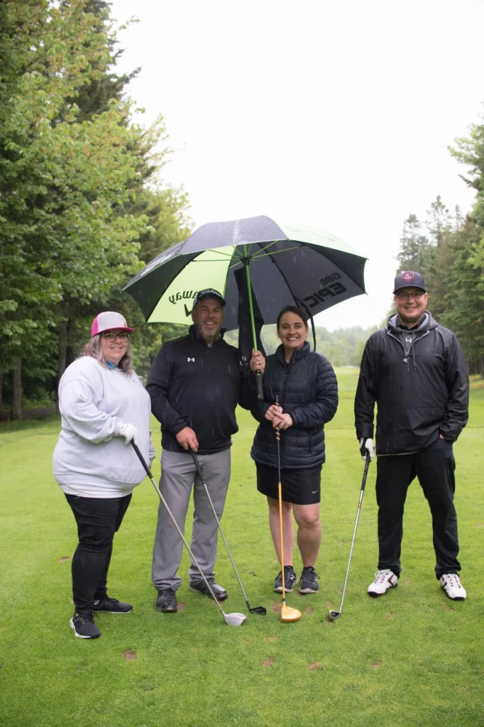 Quatre golfeurs posent sous la pluie