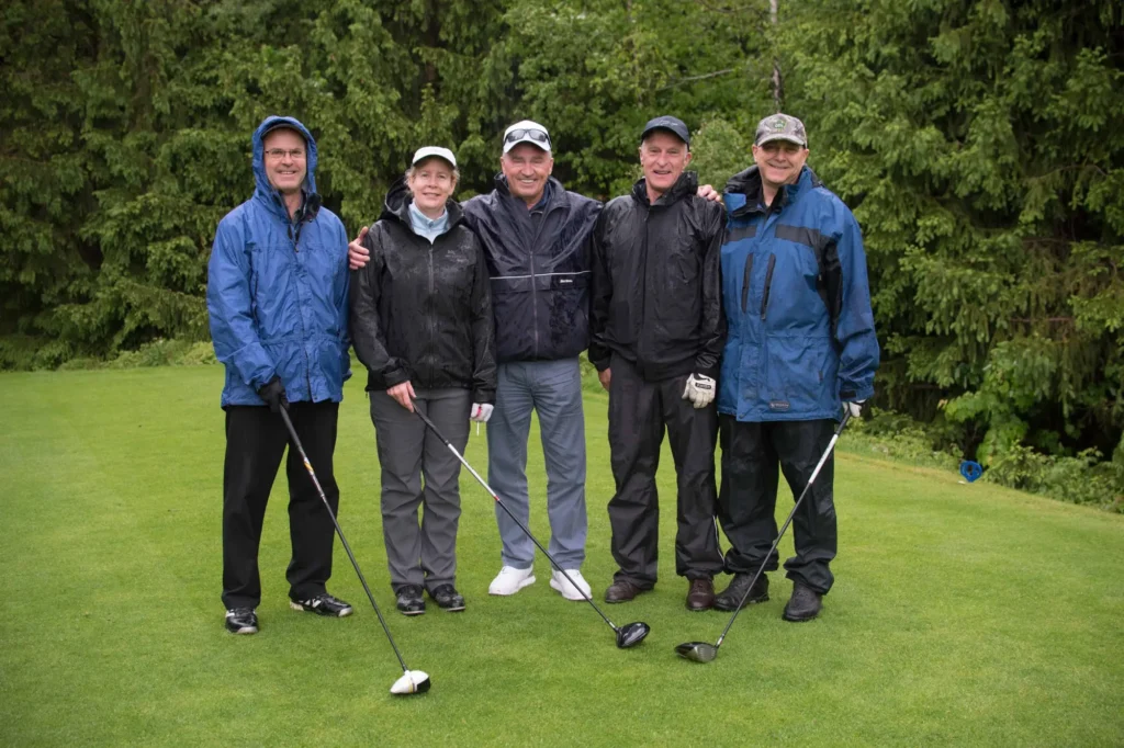 Cinq golfeurs sous la pluie sur un green