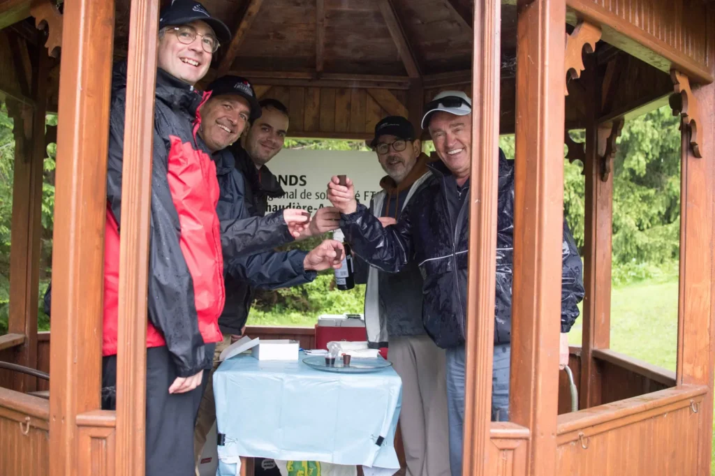 Cinq hommes trinquent sous un kiosque en bois