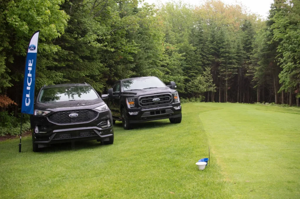 Deux véhicules Ford noirs sur pelouse forestière