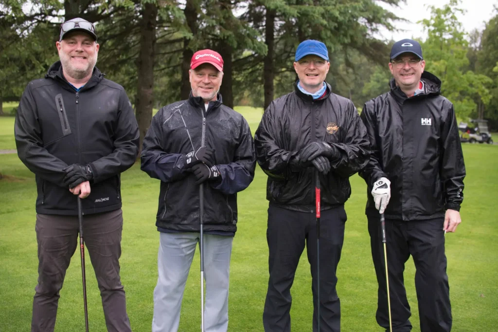 Quatre golfeurs sous la pluie sur un parcours