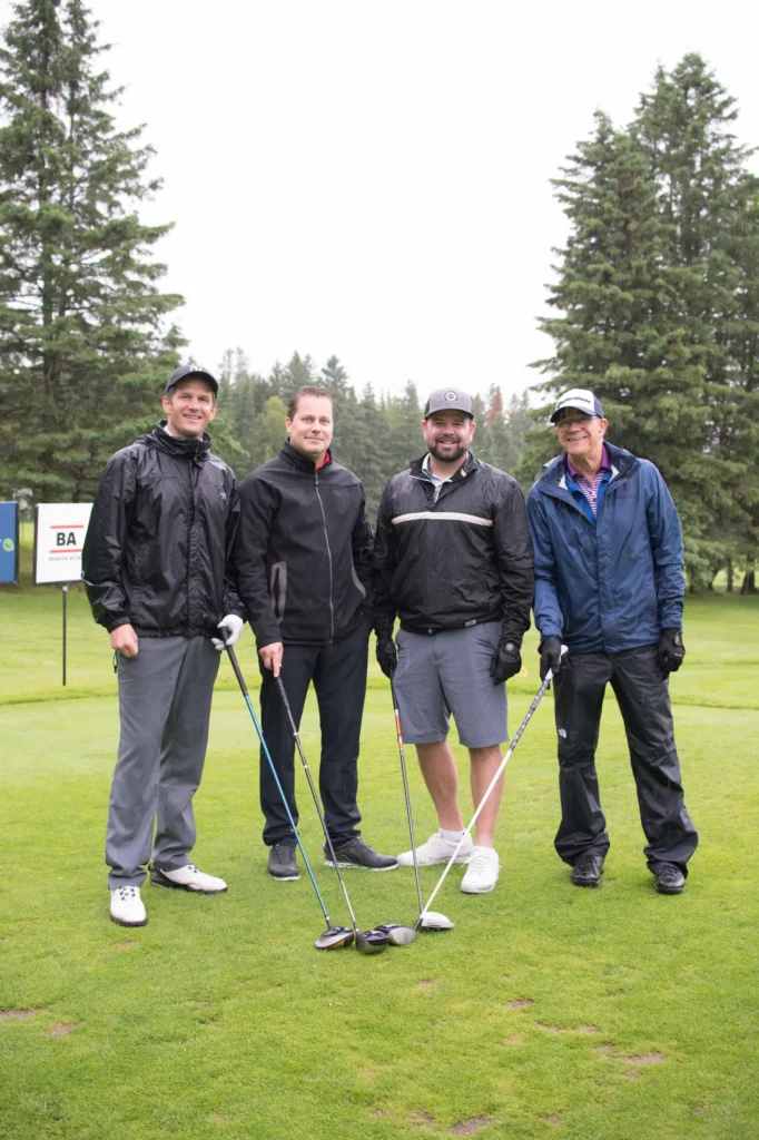 Quatre golfeurs posant sur un parcours verdoyant