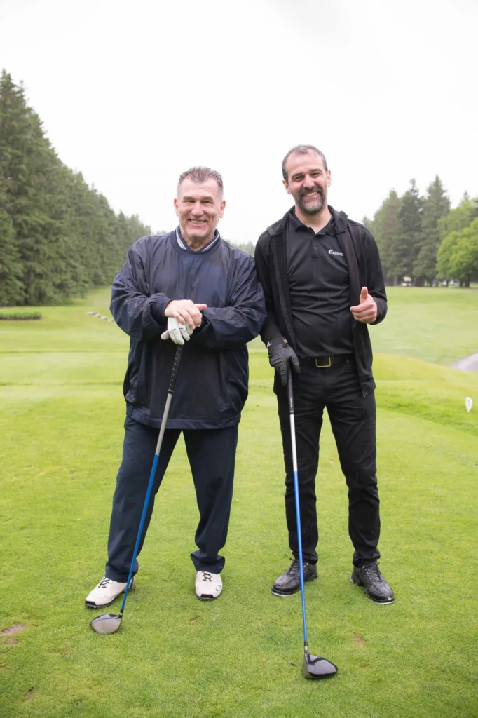 Deux hommes souriants sur un parcours de golf