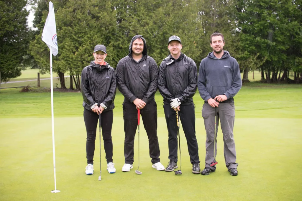Quatre golfeurs posent sous la pluie