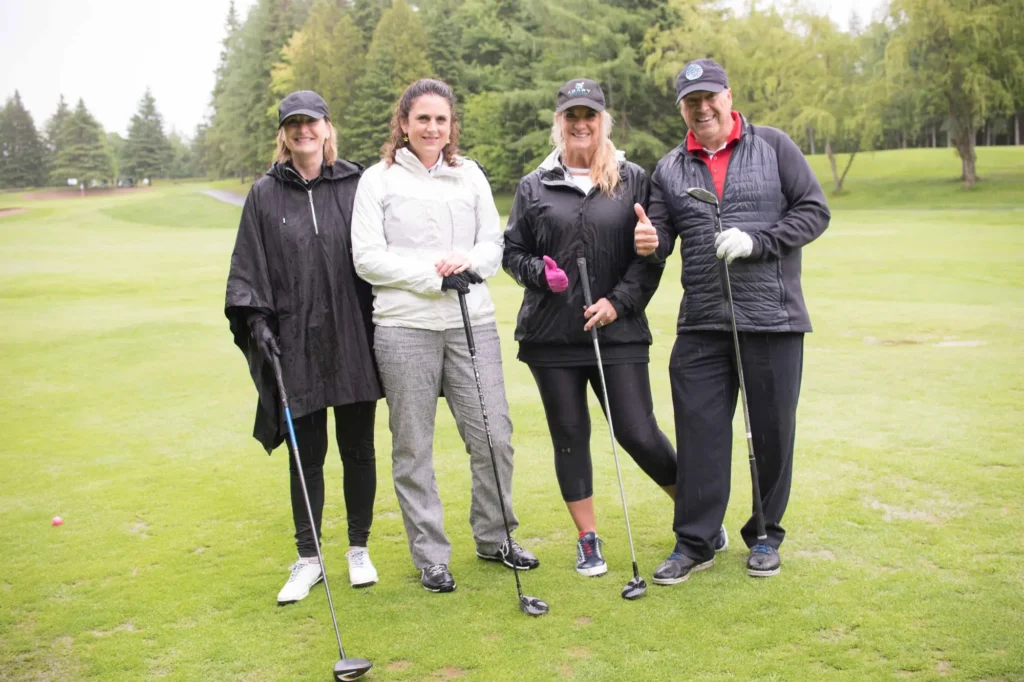 Quatre golfeurs souriants sur un parcours verdoyant