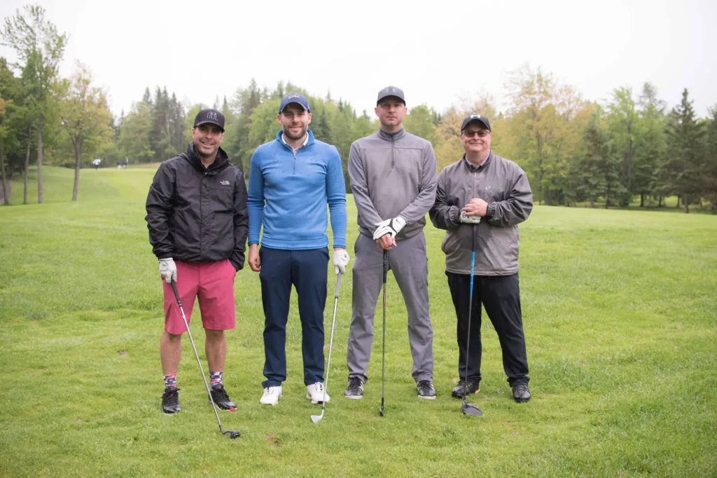 Quatre golfeurs posant sur un parcours verdoyant