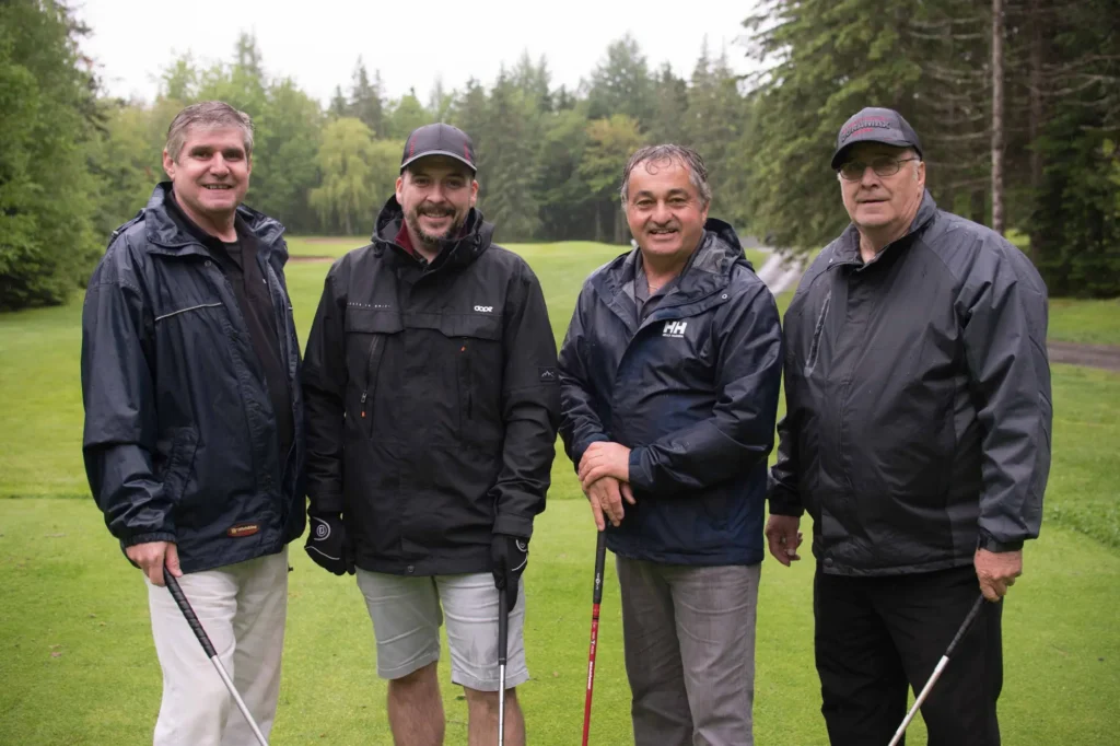 Quatre hommes posant sur un parcours de golf