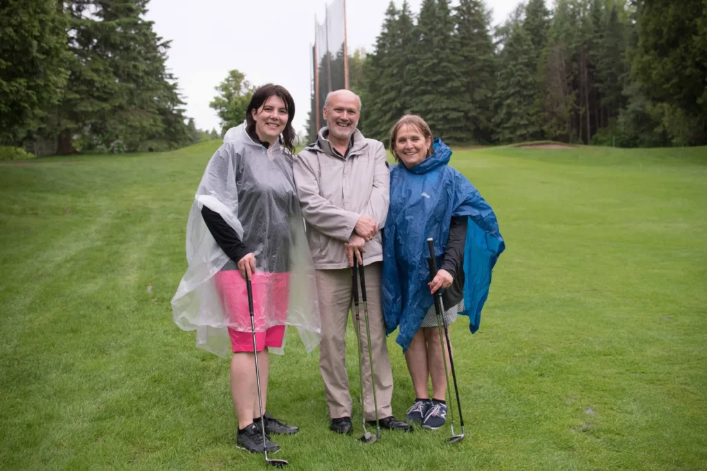 Trois golfeurs en ponchos sous la pluie