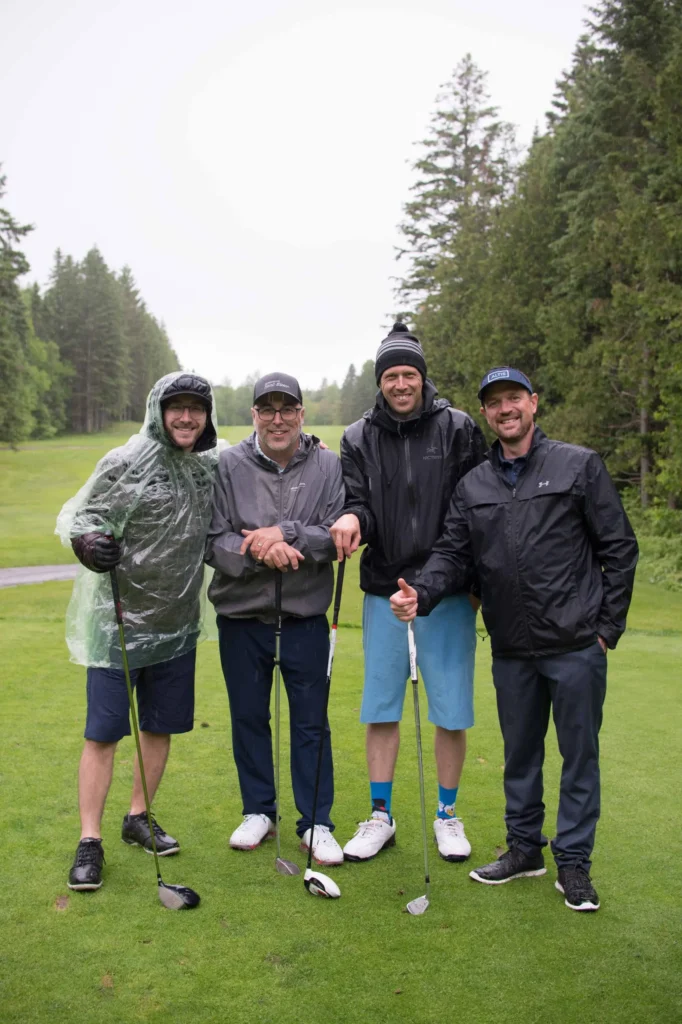 Quatre hommes jouant au golf sous la pluie