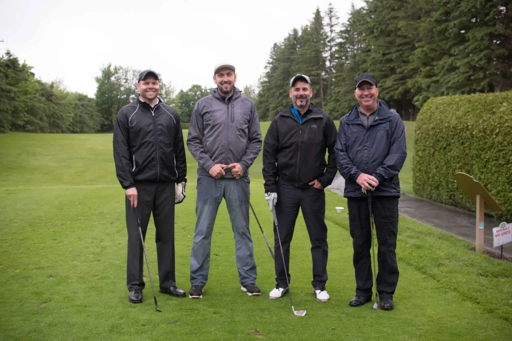 Quatre hommes posant sur un terrain de golf