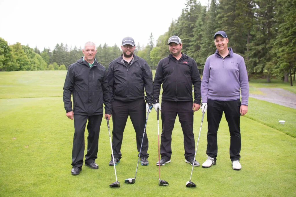 Quatre golfeurs posant sur un parcours verdoyant